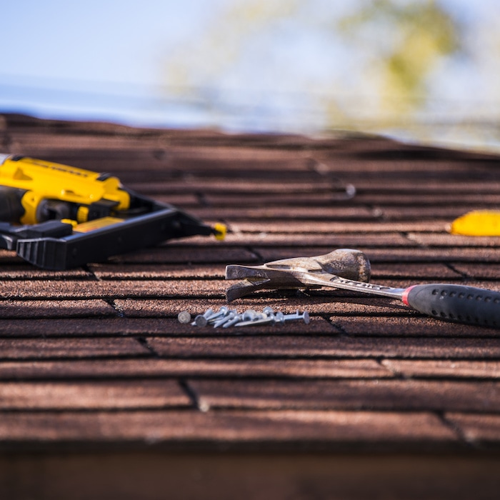 Tools laid out on a shingled roof during a repair project.