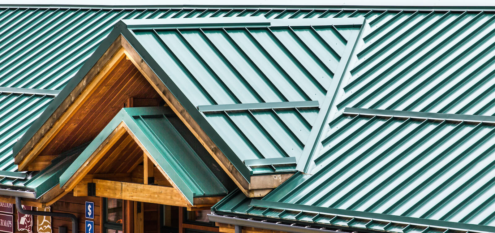Close-up of a green metal roof with detailed paneling and wooden eaves.