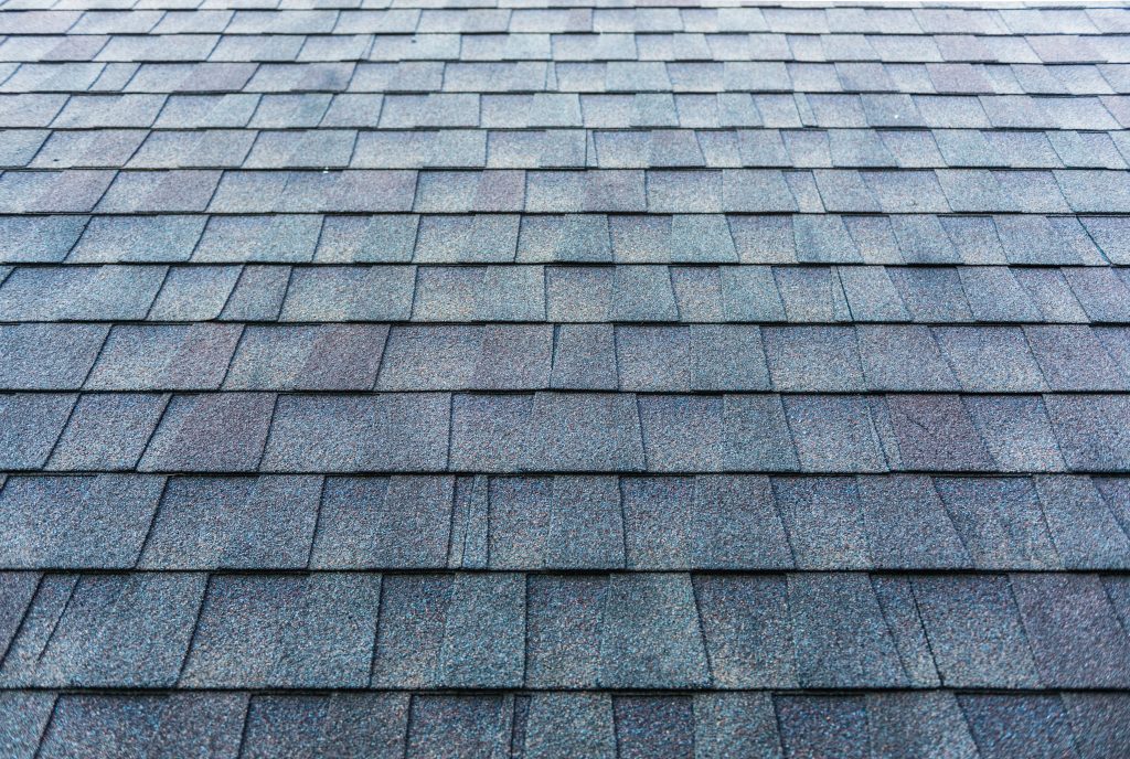 Close-up of gray asphalt roof shingles arranged in rows.