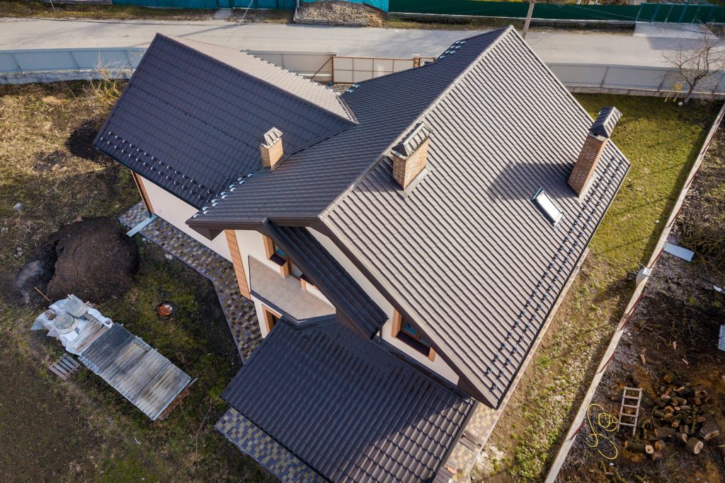 Aerial view of a modern house with a dark tiled roof and chimneys.