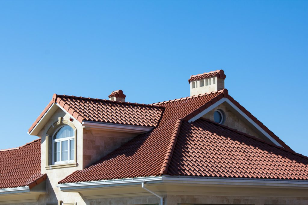 House roof with red tiles under clear blue sky.